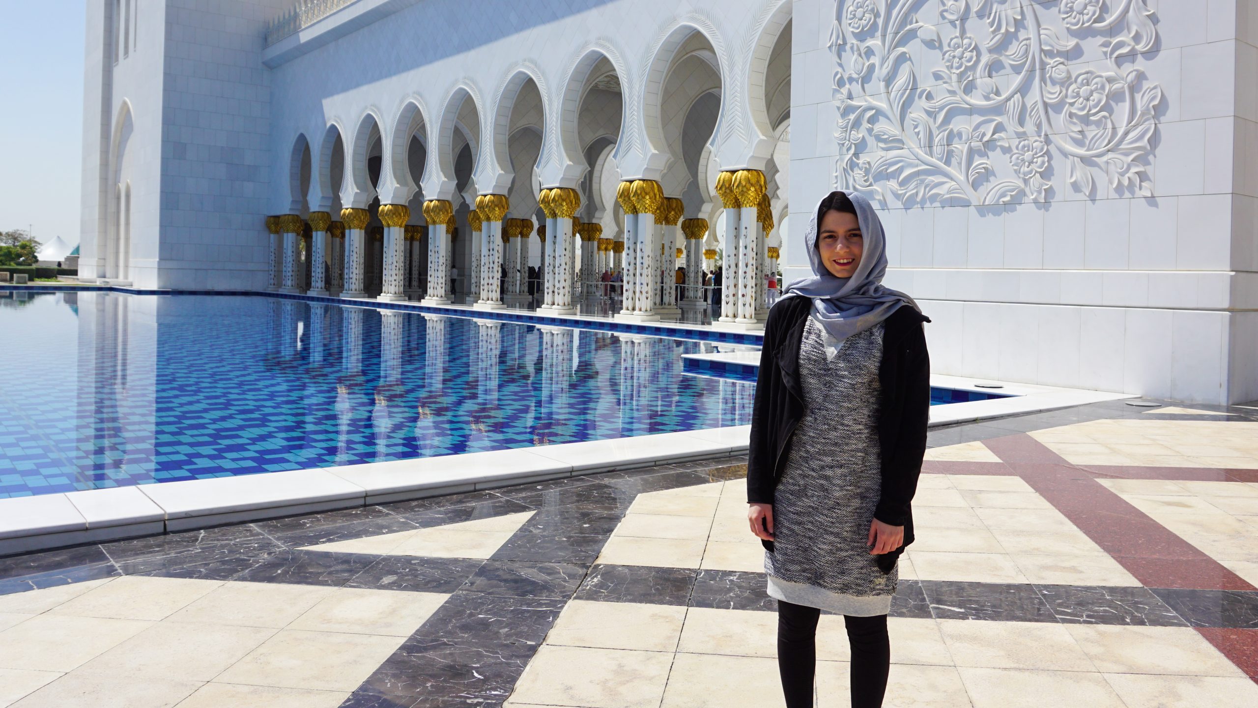 A girl standing in front of the Grand Mosque in Abu Dhabi and is covered from top to bottom