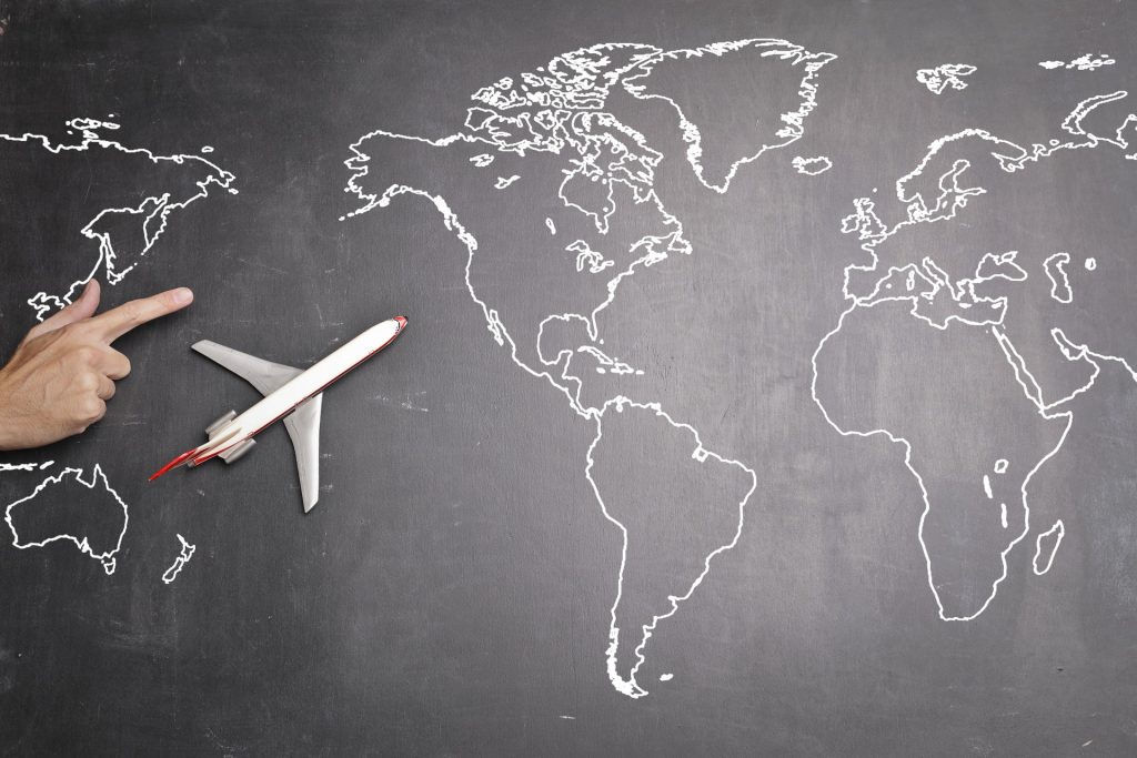 A world map drawn on a chalk board with a toy airplane on the side that show you how to plan a trip