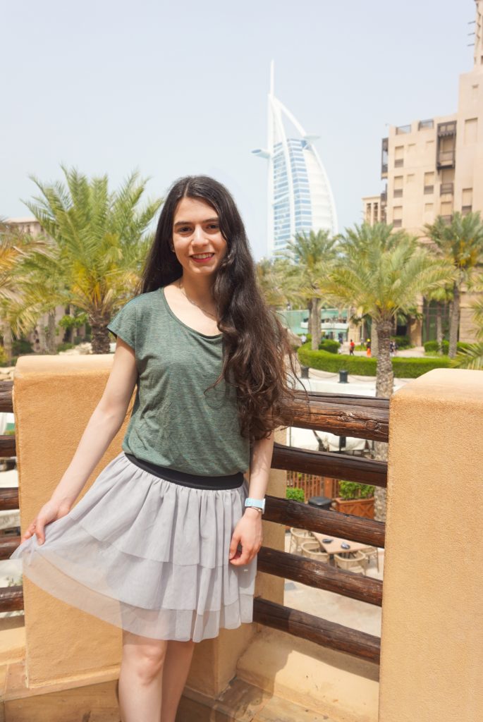 A girl standing outdoors with background the luxury hotel Burj Khalifa