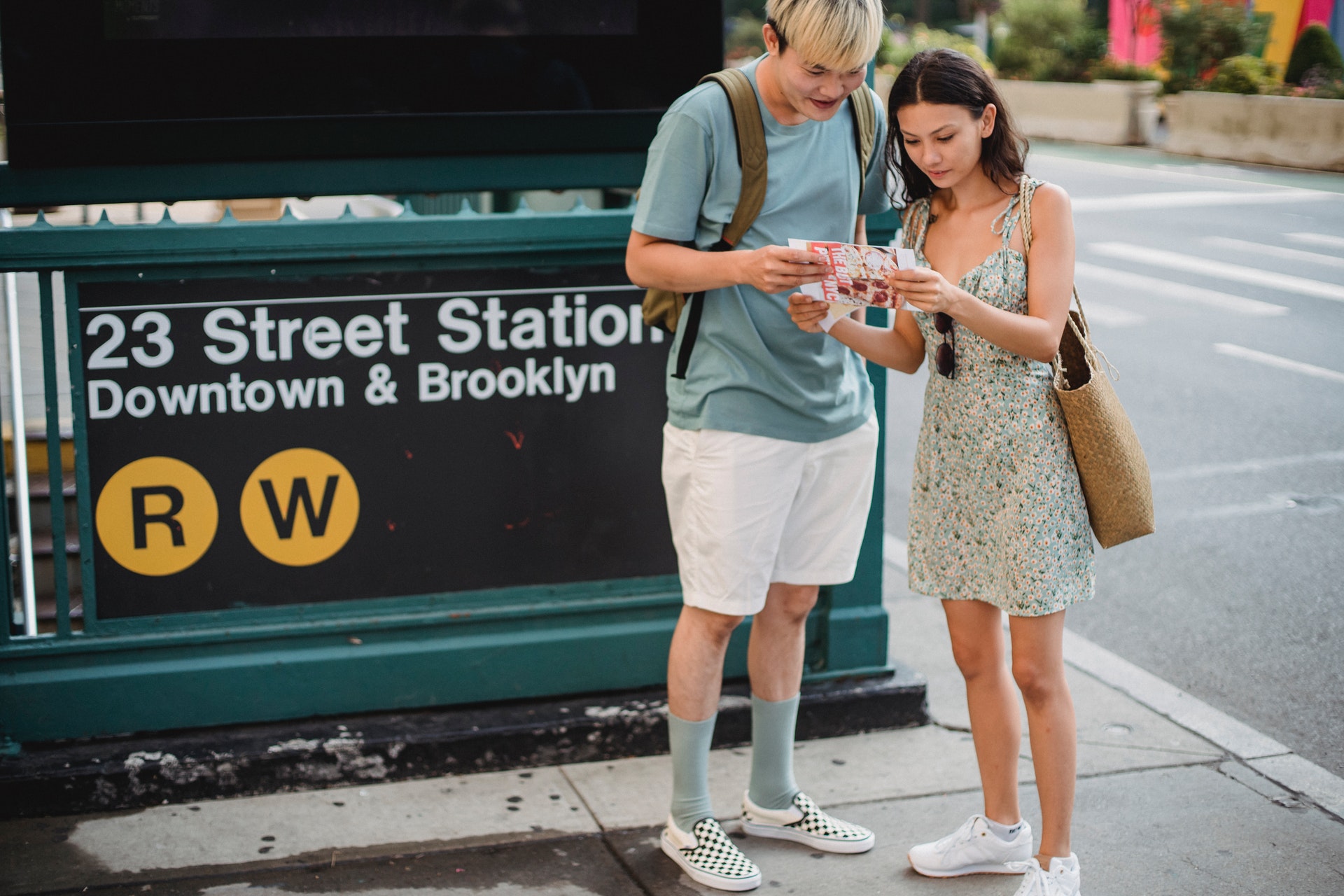 A man and a woman are looking at a map in front of a subway station in New York City