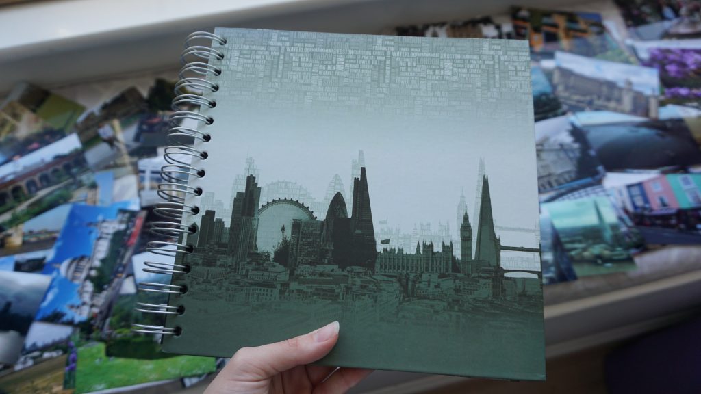 A photo album with London sights on the cover and many paper photos on the background