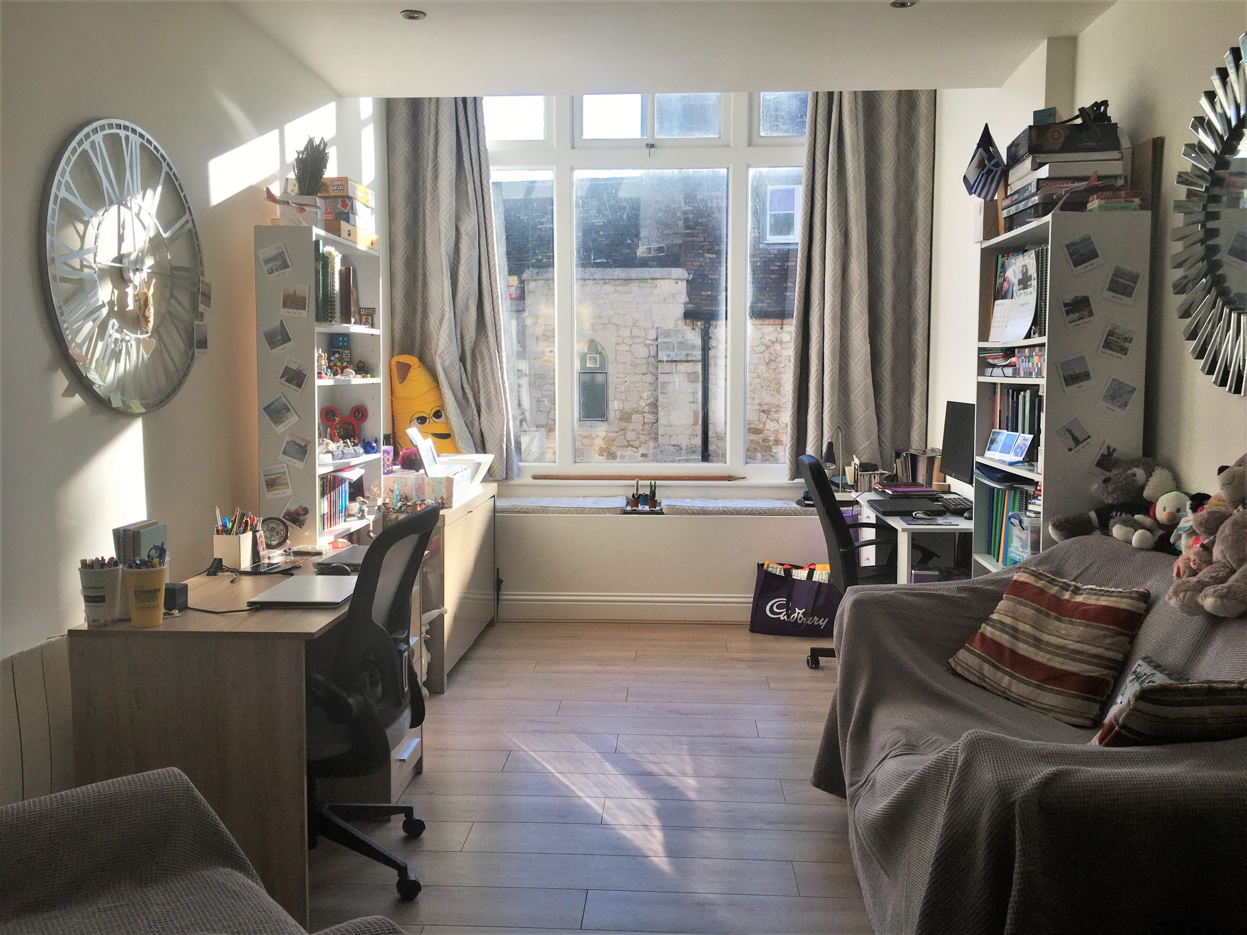 A space with two desks, two bookcases, a sofa and a window for how I spend my time at home