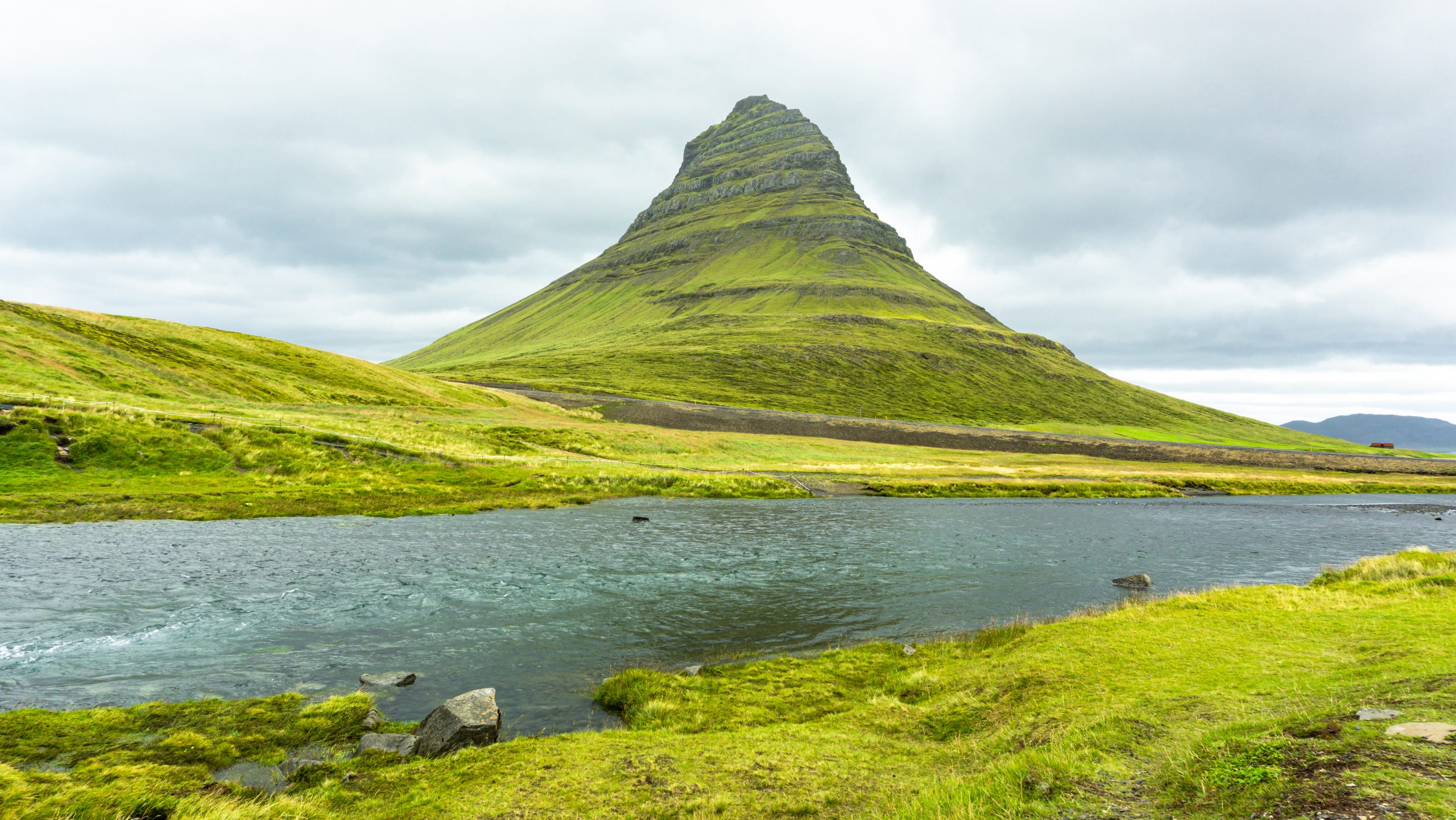 View of a river with Kirkjufell, a dome-shaped mountain at the background