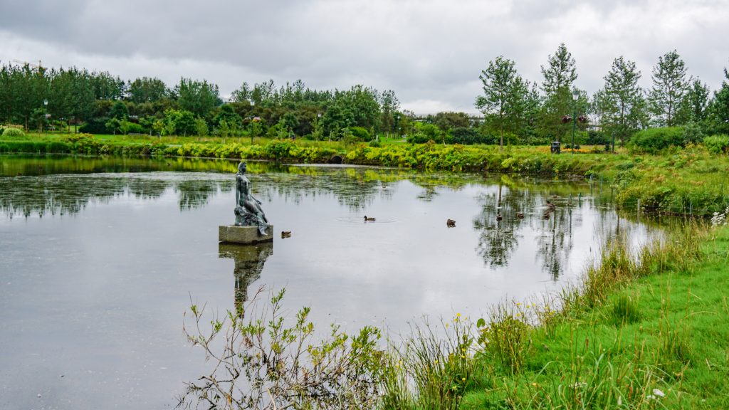 A lake with a statue in the middle of a park in Reykjavik