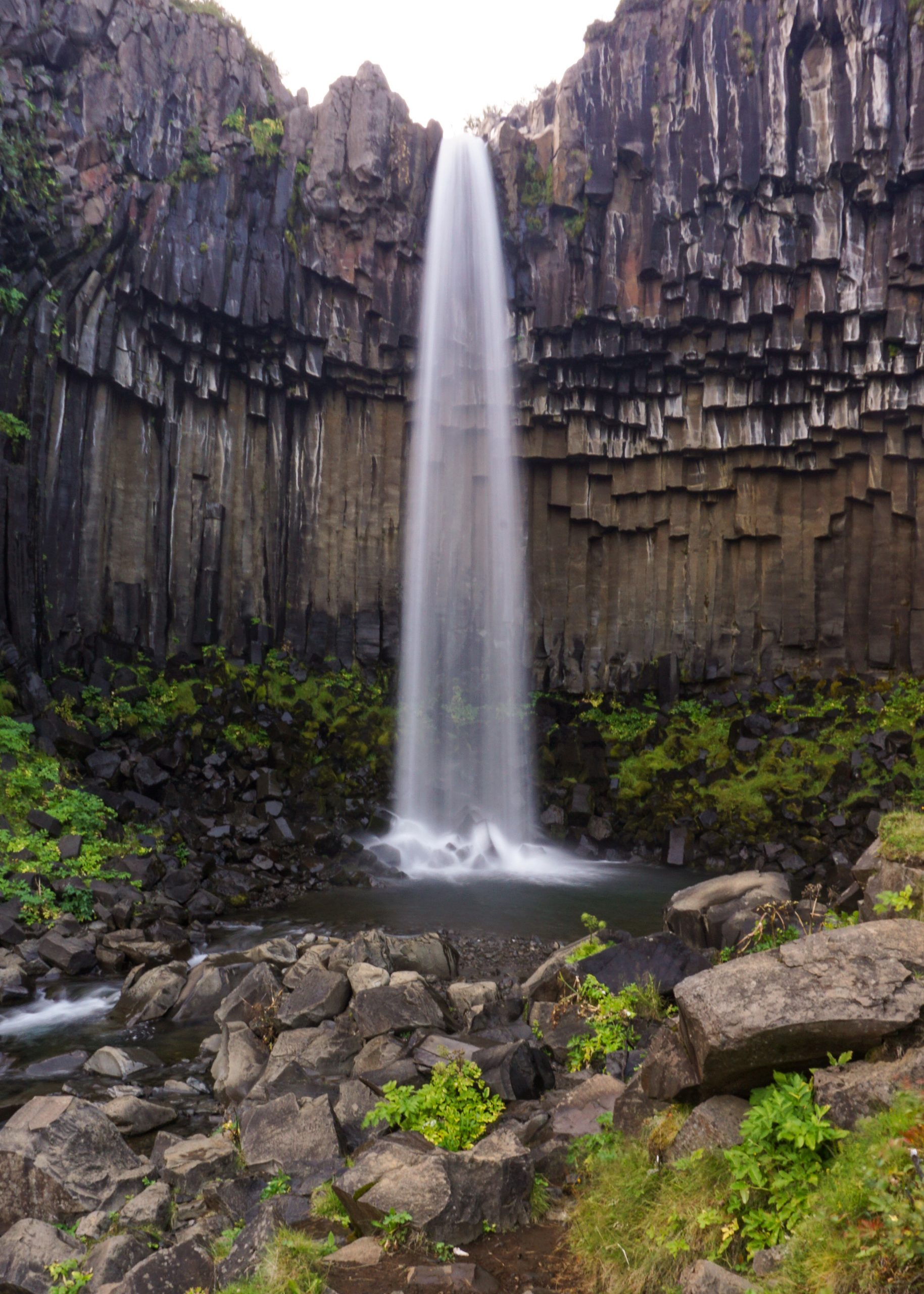 A waterfall during the Iceland road trip itinerary surrounded by columnar cliffs