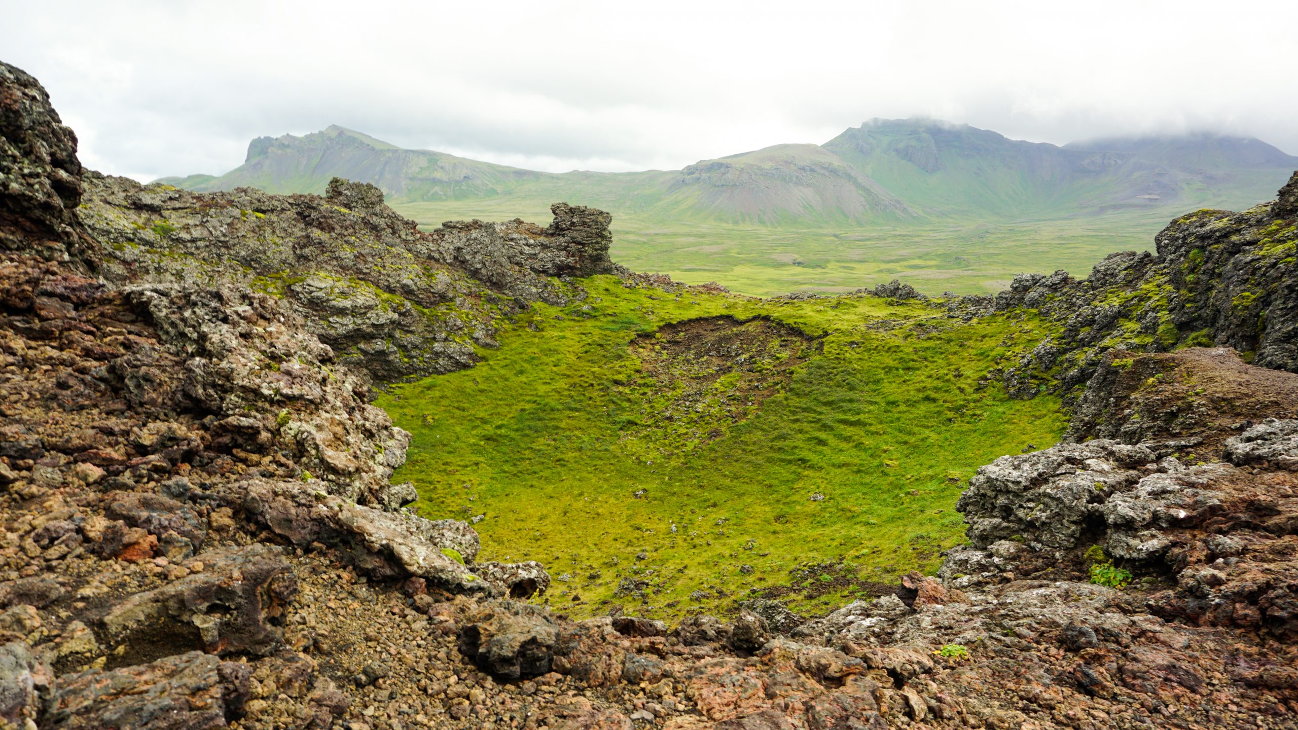 The top of a volcano crater surrounded by green vegetation